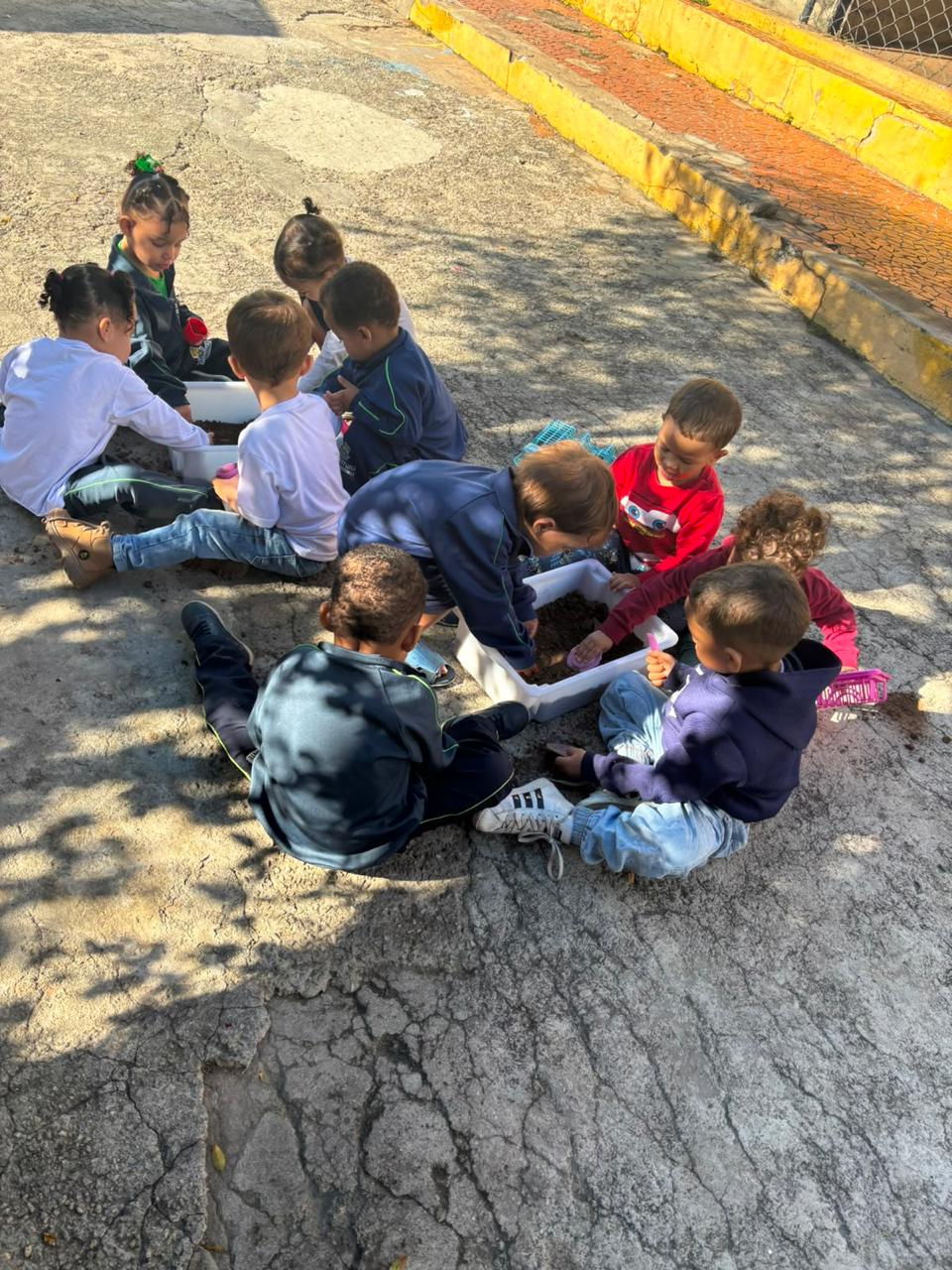 Turma da Creche fazendo atividade de jardinagem no pátio