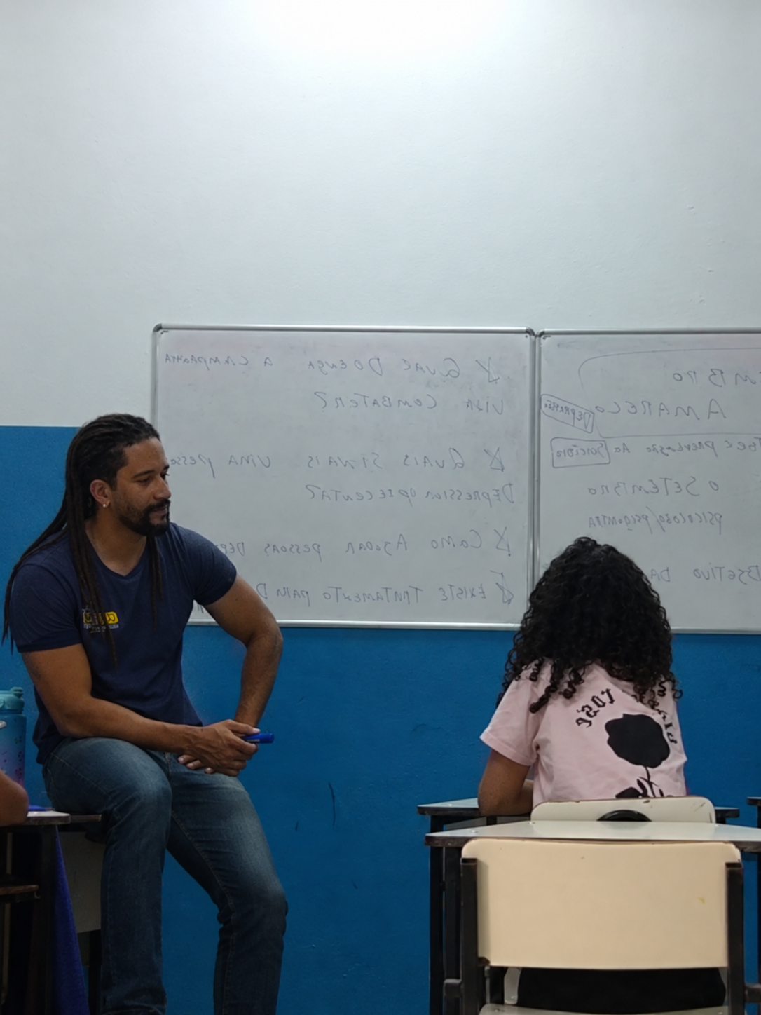 Educador sentado conversando individualmente com uma criança em sala de aula